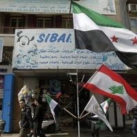 Un drapeau de la rébellion syrienne et un drapeau libanais devant une boutique dans une rue de Tripoli, au Liban, le 2 mars 2012 
